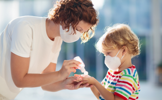 Mother and child wearing masks and using hand sanitizer